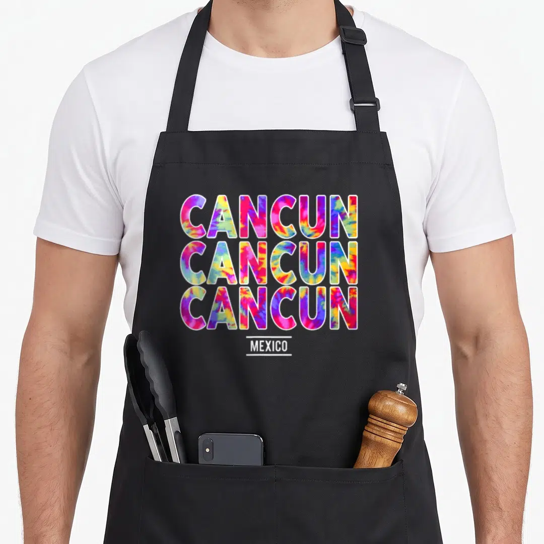 Summer spring aprons - Tie-dye CANCUN text repeated three times above MEXICO in pink blue yellow white — shown on a black cotton canvas apron against a white background