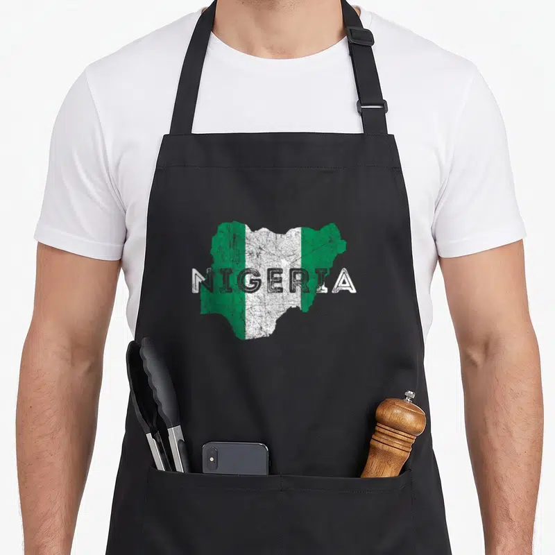 Nigerian distressed apron - Distressed map of Nigeria filled with green and white flag colors and text NIGERIA across — shown on a black cotton canvas apron against a white background