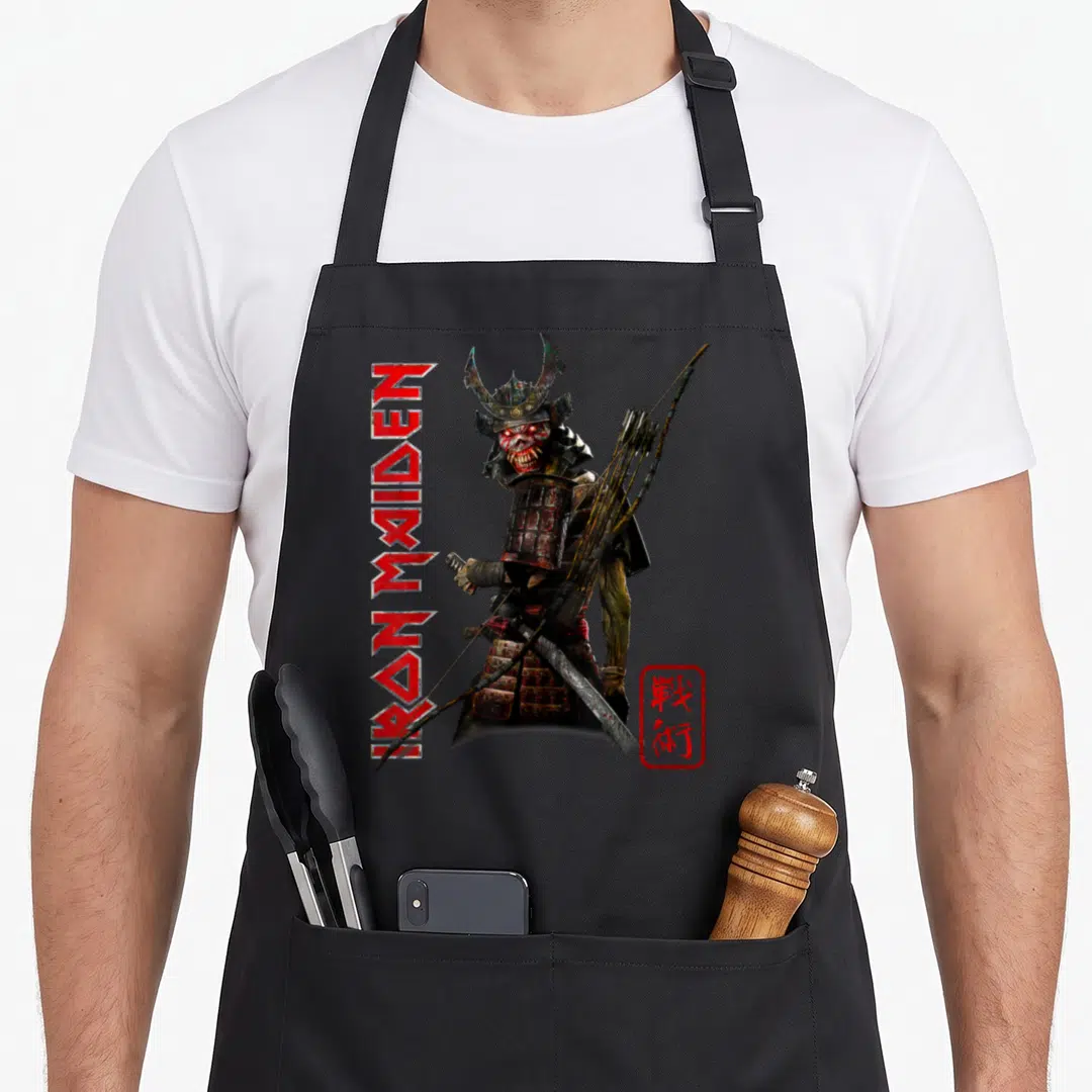 Samurai camping apron - Eddie the Head as samurai with vertical IRON MAIDEN text and red seal — shown on a black cotton canvas apron against a white background