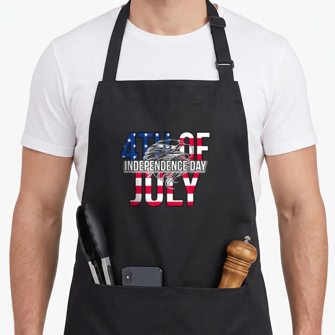 Independence flag 4th of july apron - Eagle head overlapping 4TH OF INDEPENDENCE DAY JULY text in red white blue stars — shown on a black cotton canvas apron against a white background