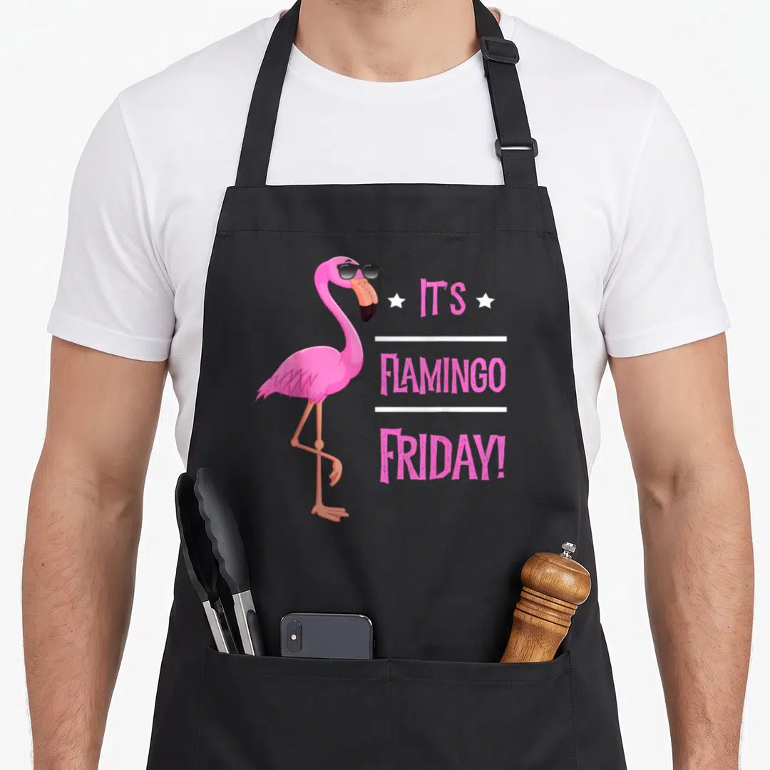 Flamingo bird apron - Pink cartoon flamingo in black sunglasses beside stacked text It's Flamingo Friday with white — shown on a black cotton canvas apron against a white background