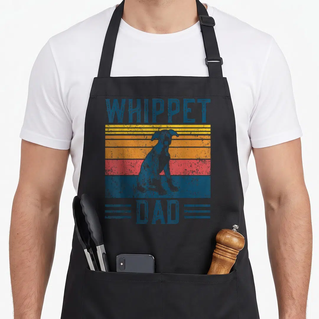 Vintage whippet dog apron - Retro striped graphic of sitting whippet with WHIPPET DAD text in blue and warm tones — shown on a black cotton canvas apron against a white background