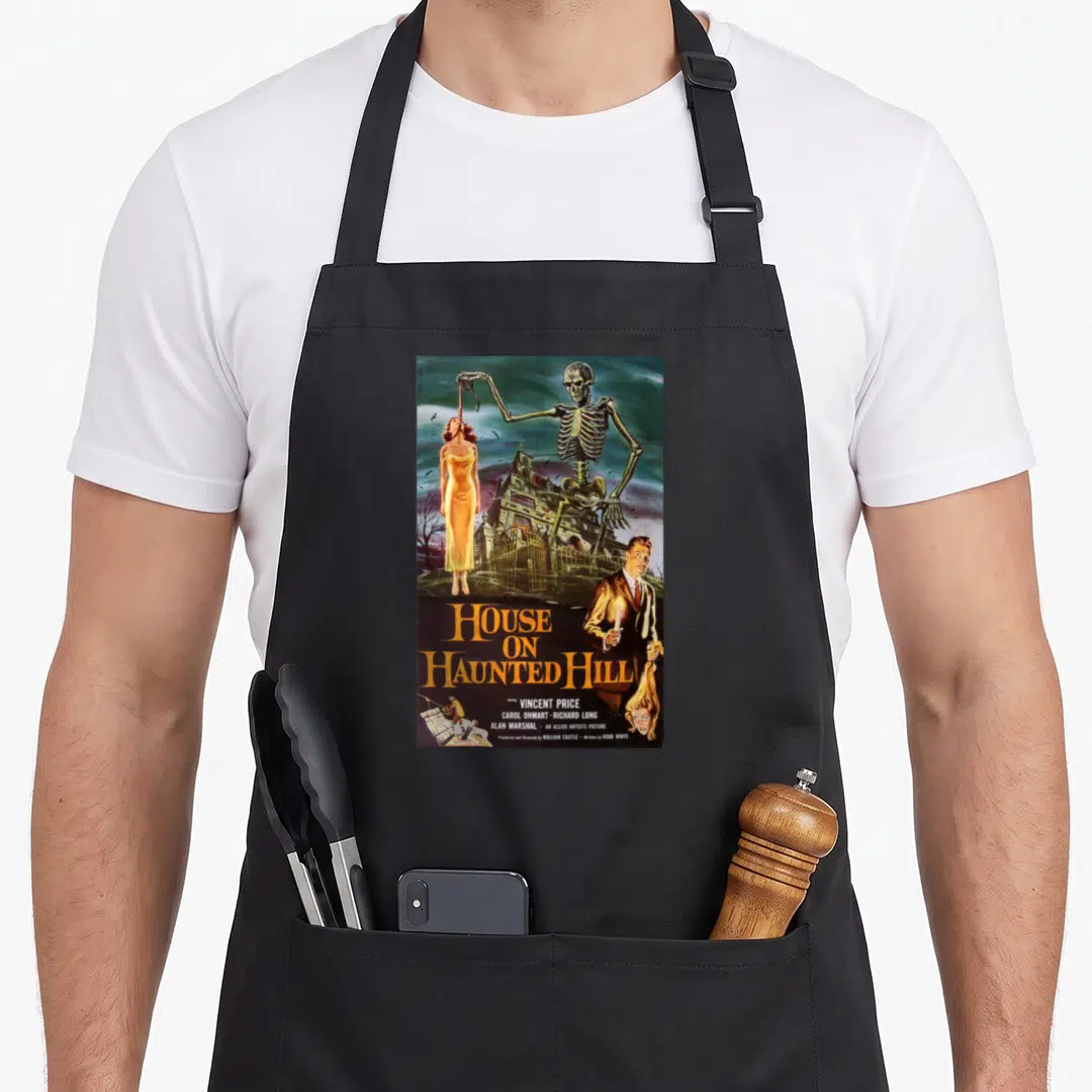 Vintage movie poster apron - Retro movie poster art showing a giant skeleton lifting a woman over a house with yellow — shown on a black cotton canvas apron against a white background