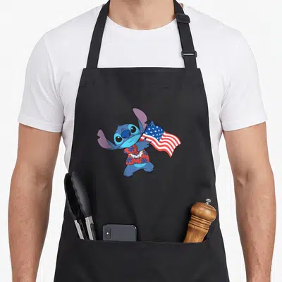Stitch tropical print aprons - Blue cartoon character in red floral shirt holding USA flag with white lei — shown on a black cotton canvas apron against a white background