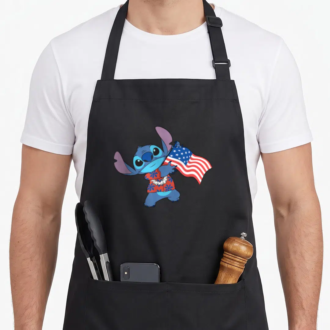 Stitch tropical print aprons - Blue cartoon character in red floral shirt holding USA flag with white lei — shown on a black cotton canvas apron against a white background