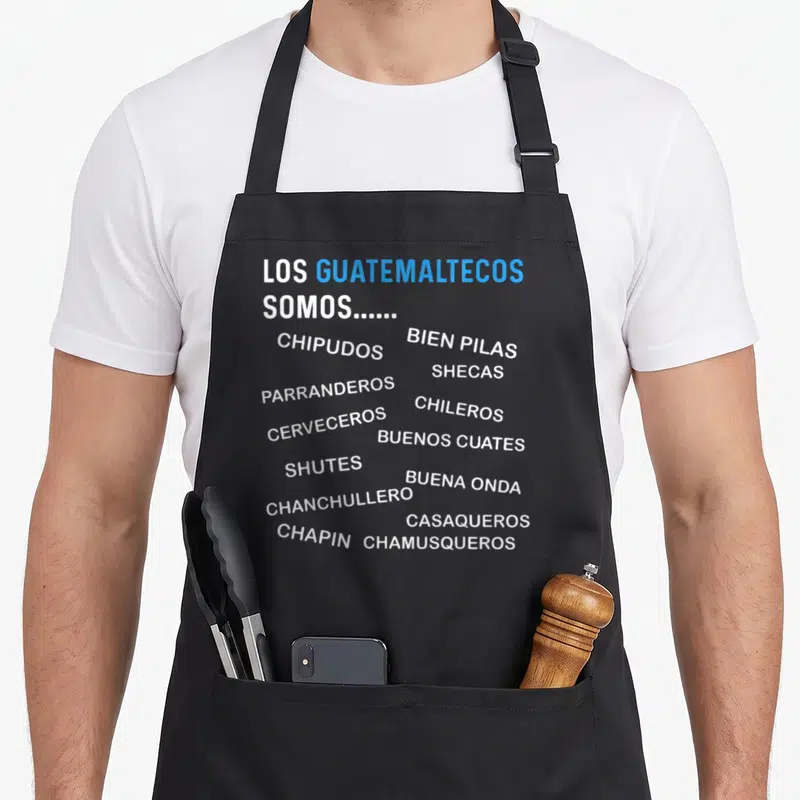 Map guatemalan aprons - White and blue Guatemalan slang words like Chipudos, Chapin, and Chileros on black fabric — shown on a black cotton canvas apron against a white background