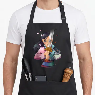 Warrior anime apron - Cartoon woman holding sword vertically in front of face with pink petals and blue armor details — shown on a black cotton canvas apron against a white background