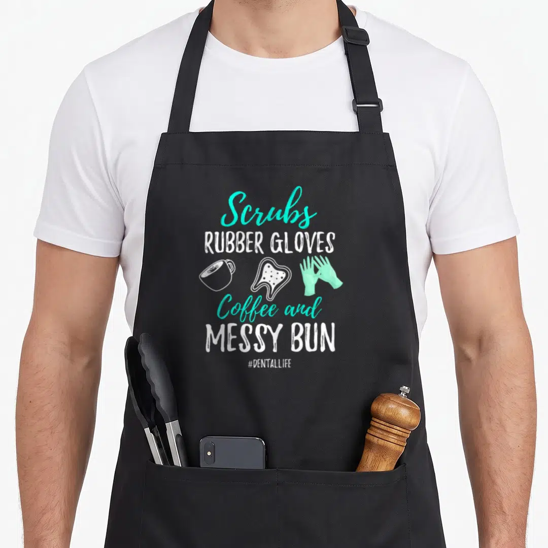 Dental hygienist life apron - Stacked text listing scrubs rubber gloves coffee messy bun with coffee tooth and glove — shown on a black cotton canvas apron against a white background