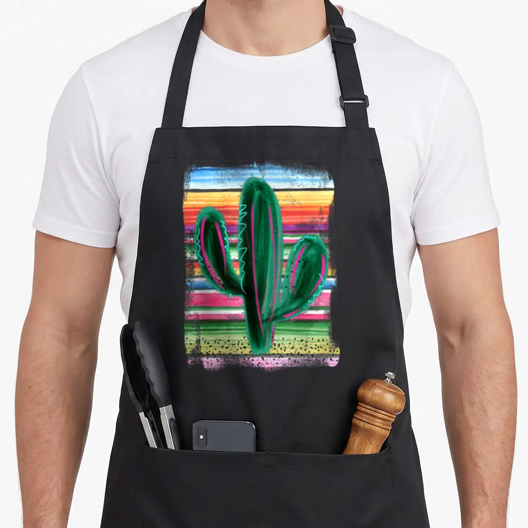 Serape cactus apron - Green watercolor cactus with pink and blue accents over horizontal multicolored stripes — shown on a black cotton canvas apron against a white background