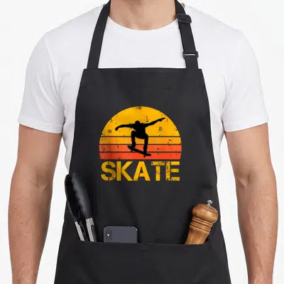 Skateboarding skateboarder apron - Retro SKATE text under black skater silhouette and striped sun — shown on a black cotton canvas apron against a white background