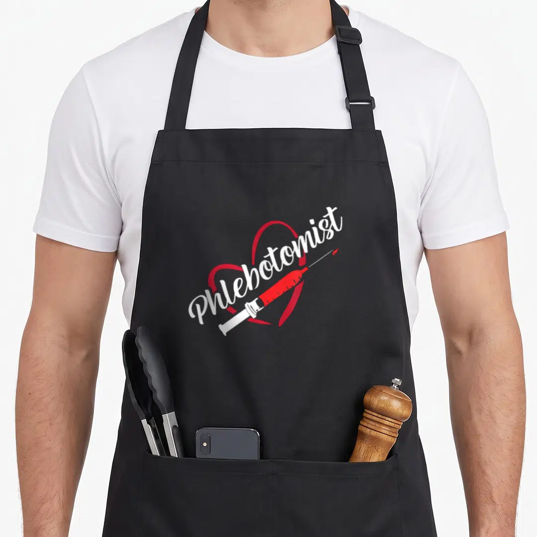 Syringe phlebotomist apron - White Phlebotomist script over red heart outline with red and white syringe on black — shown on a black cotton canvas apron against a white background