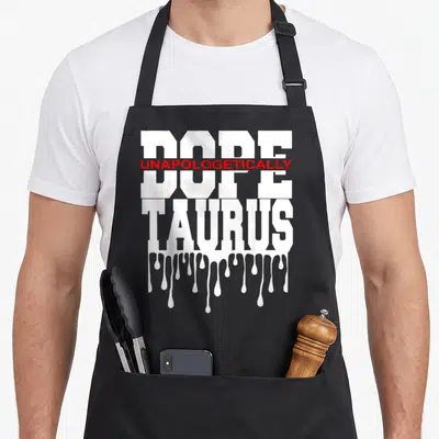 Taurus king apron - Stacked white text DOPE and TAURUS with red UNAPOLOGETICally overlay and dripping paint effect — shown on a black cotton canvas apron against a white background