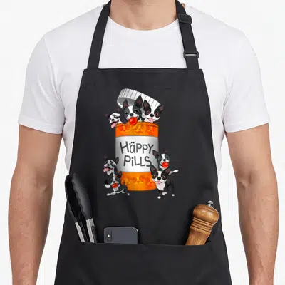 Boston tablet apron - Orange pill bottle with six Boston Terriers holding red pills and text Häppy PiLLS — shown on a black cotton canvas apron against a white background