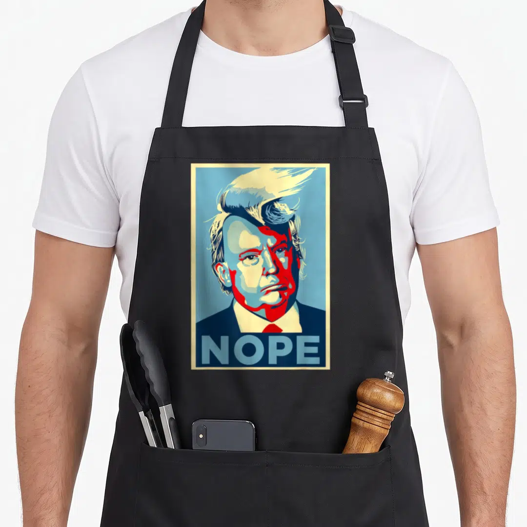 Nope hair apron - Retro red blue cream Trump portrait with NOPE text bar at bottom — shown on a black cotton canvas apron against a white background
