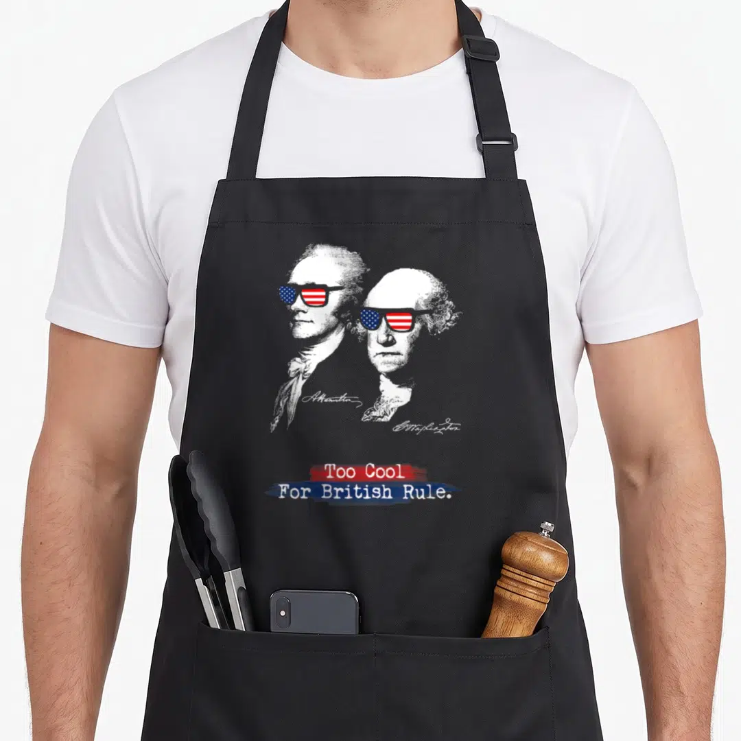Rule washington apron - Two Founding Father portraits with flag sunglasses and Too Cool For British Rule text — shown on a black cotton canvas apron against a white background
