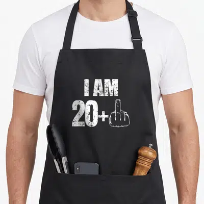 21st bday apron - White distressed I AM 20+ text with middle finger hand gesture — shown on a black cotton canvas apron against a white background