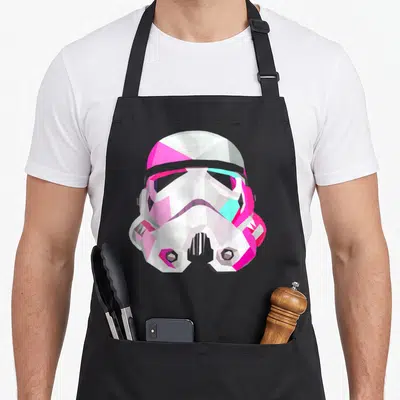 Geometricprism star war apron - Geometric white pink cyan stormtrooper helmet on black apron — shown on a black cotton canvas apron against a white background