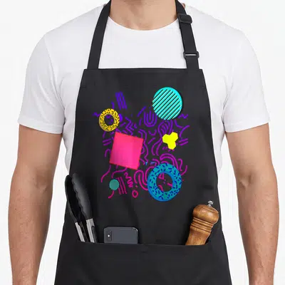 Geometric memphis apron - Abstract pink square, striped teal circle, and dotted donuts in purple, pink, yellow, blue — shown on a black cotton canvas apron against a white background
