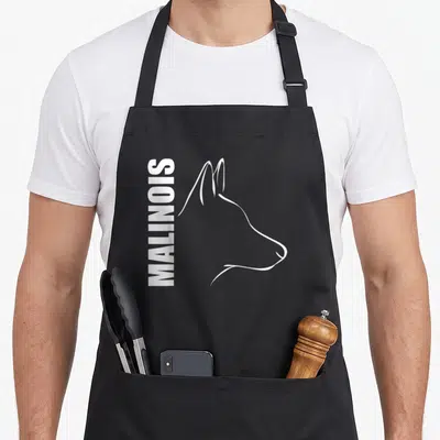 Profile dog apron - Vertical MALINOIS text beside white line-art dog head profile on black fabric — shown on a black cotton canvas apron against a white background