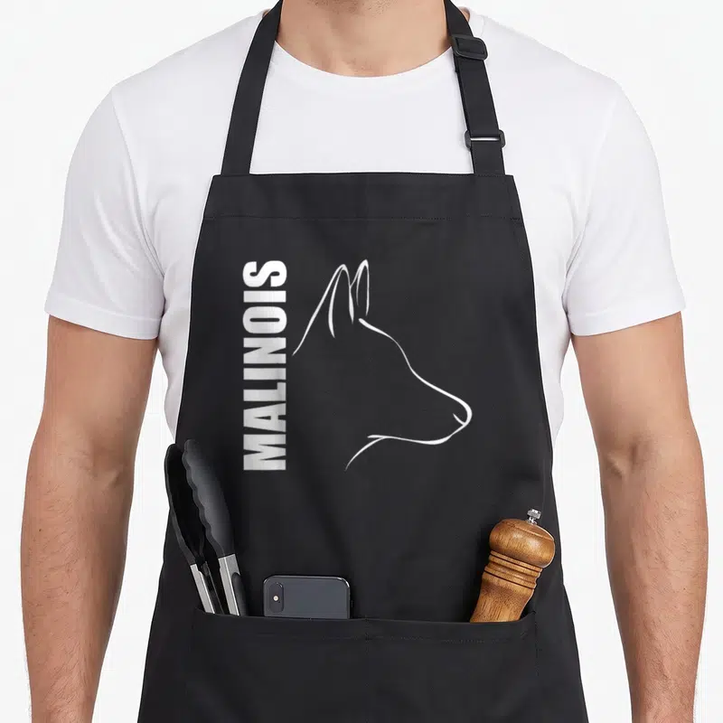 Profile dog apron - Vertical MALINOIS text beside white line-art dog head profile on black fabric — shown on a black cotton canvas apron against a white background