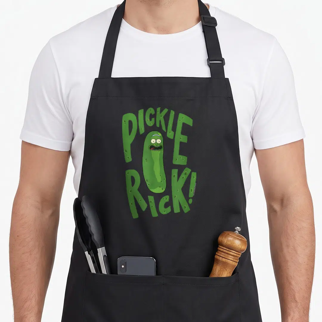Cartoon pickle apron - Pickle Rick character between green PICKLE RICK! text with white eyes — shown on a black cotton canvas apron against a white background