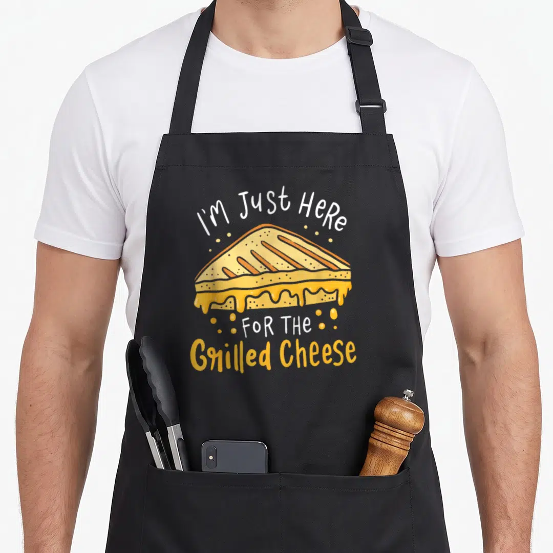 Grilled cheese apron - Cartoon grilled cheese sandwich with melting yellow cheese and white and orange text reading I'm — shown on a black cotton canvas apron against a white background