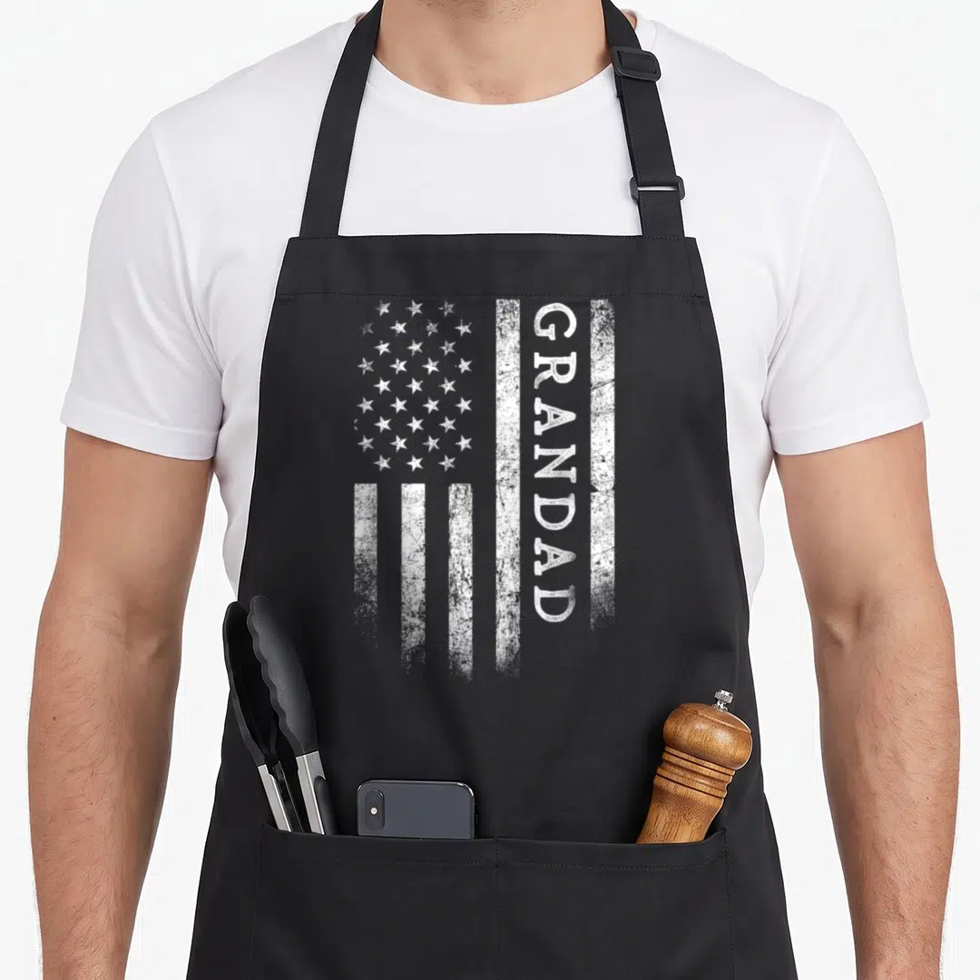 Flag grandad aprons - Distressed white USA flag with vertical GRANDAD text on black bib apron — shown on a black cotton canvas apron against a white background