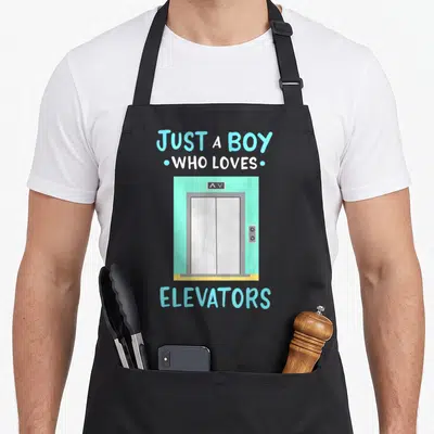 Funny elevator apron - Cartoon elevator with JUST A BOY WHO LOVES ELEVATORS text in blue and white — shown on a black cotton canvas apron against a white background