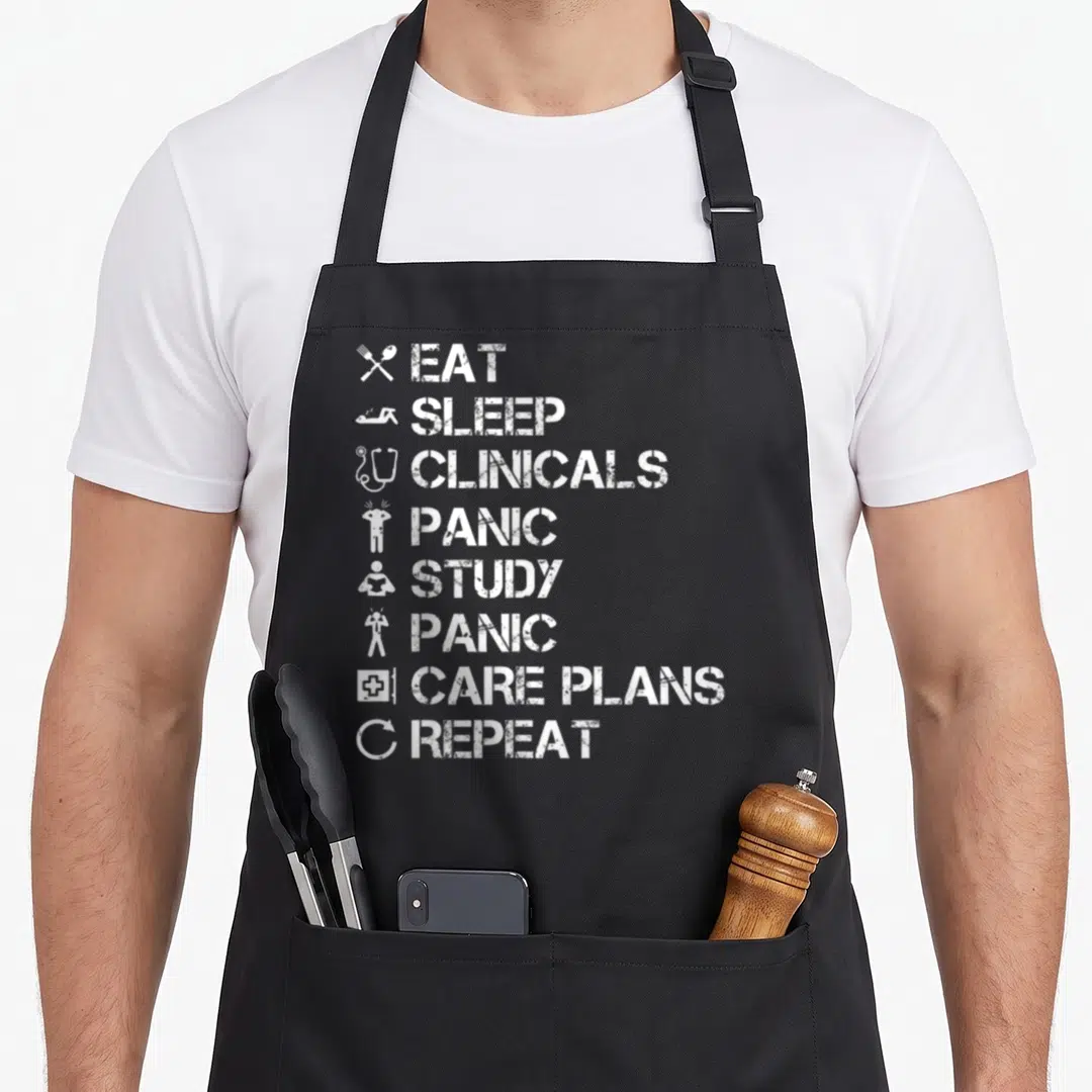 Vintage nurse nursing student apron - White distressed text listing eat sleep clinicals panic study care plans repeat — shown on a black cotton canvas apron against a white background