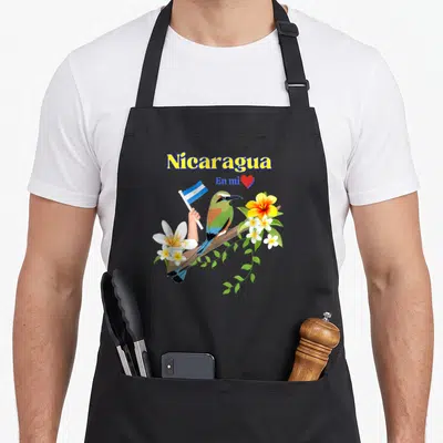 Nicaragua patriotic apron - Bird holding flag on branch with Nicaragua En mi text and red heart — shown on a black cotton canvas apron against a white background