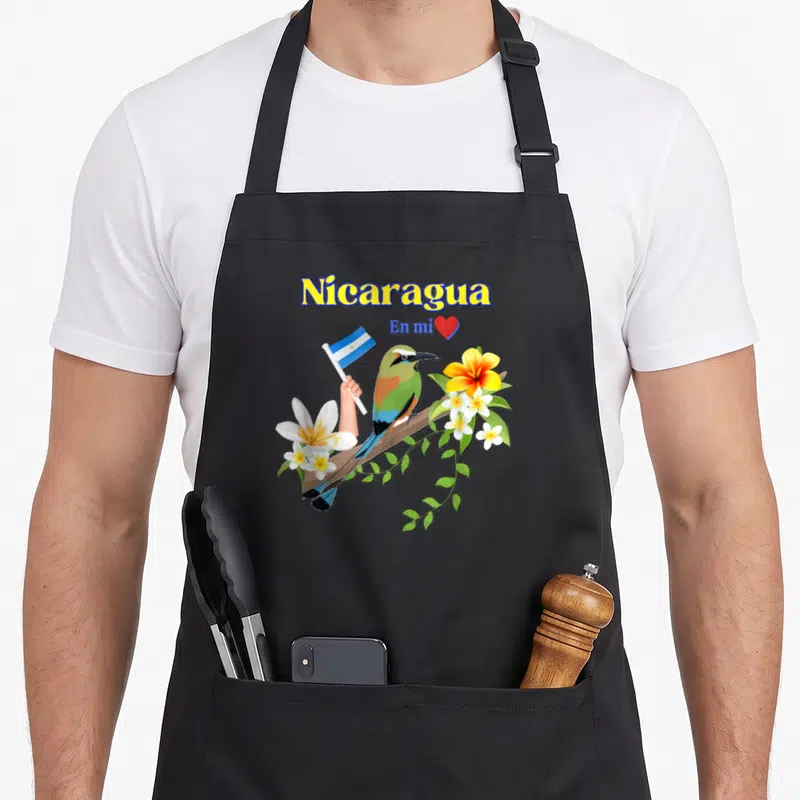 Nicaragua patriotic apron - Bird holding flag on branch with Nicaragua En mi text and red heart — shown on a black cotton canvas apron against a white background