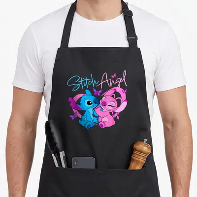 Angel butterfly apron - Stitch and Angel hugging with blue and pink butterflies and script text — shown on a black cotton canvas apron against a white background