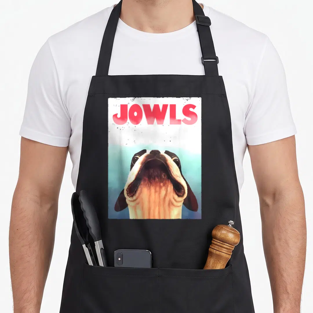 Jowl dog apron - Red JOWLS text above a realistic dog head looking upward on white and blue background — shown on a black cotton canvas apron against a white background