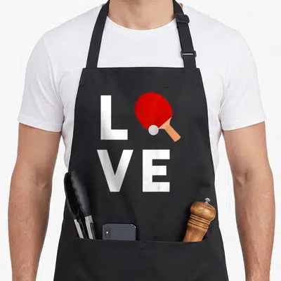 Ping pong table apron - Red ping pong paddle and white ball replacing O in white LOVE text — shown on a black cotton canvas apron against a white background