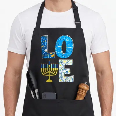 Decoration hanukkah apron - LOVE text with yellow menorah V and patterned blue white letters — shown on a black cotton canvas apron against a white background