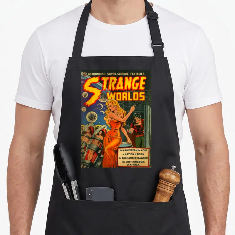Sci pin up apron - Vintage comic cover with woman in orange dress, stasis pods, and title Strange Worlds in yellow — shown on a black cotton canvas apron against a white background