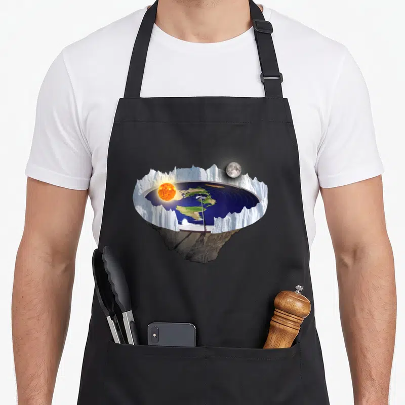 Earth flat apron - Realistic flat earth disc with jagged white ice wall, orange sun, grey moon, and blue ocean on rocky — shown on a black cotton canvas apron against a white background