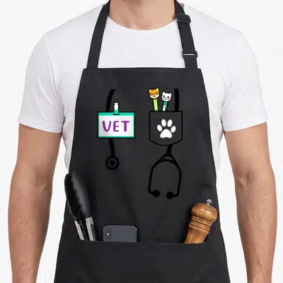 Veterinarian doctor apron - VET badge on stethoscope with orange dog and white cat in grey pocket with white paw print — shown on a black cotton canvas apron against a white background