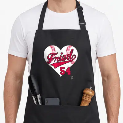 Max baseball apron - Fried 54 text on white heart baseball shape with red stitching — shown on a black cotton canvas apron against a white background