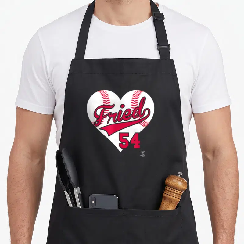 Max baseball apron - Fried 54 text on white heart baseball shape with red stitching — shown on a black cotton canvas apron against a white background