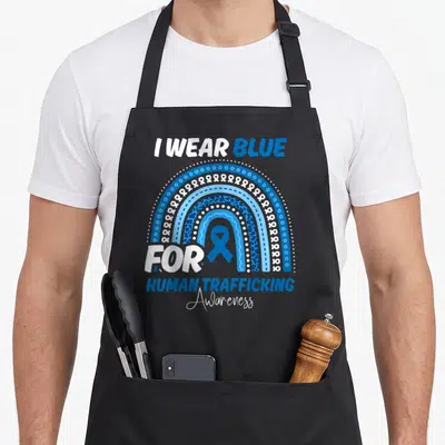 Trafficking rainbow apron - I WEAR BLUE FOR HUMAN TRAFFICKING Awareness text with blue ribbon inside rainbow arch — shown on a black cotton canvas apron against a white background