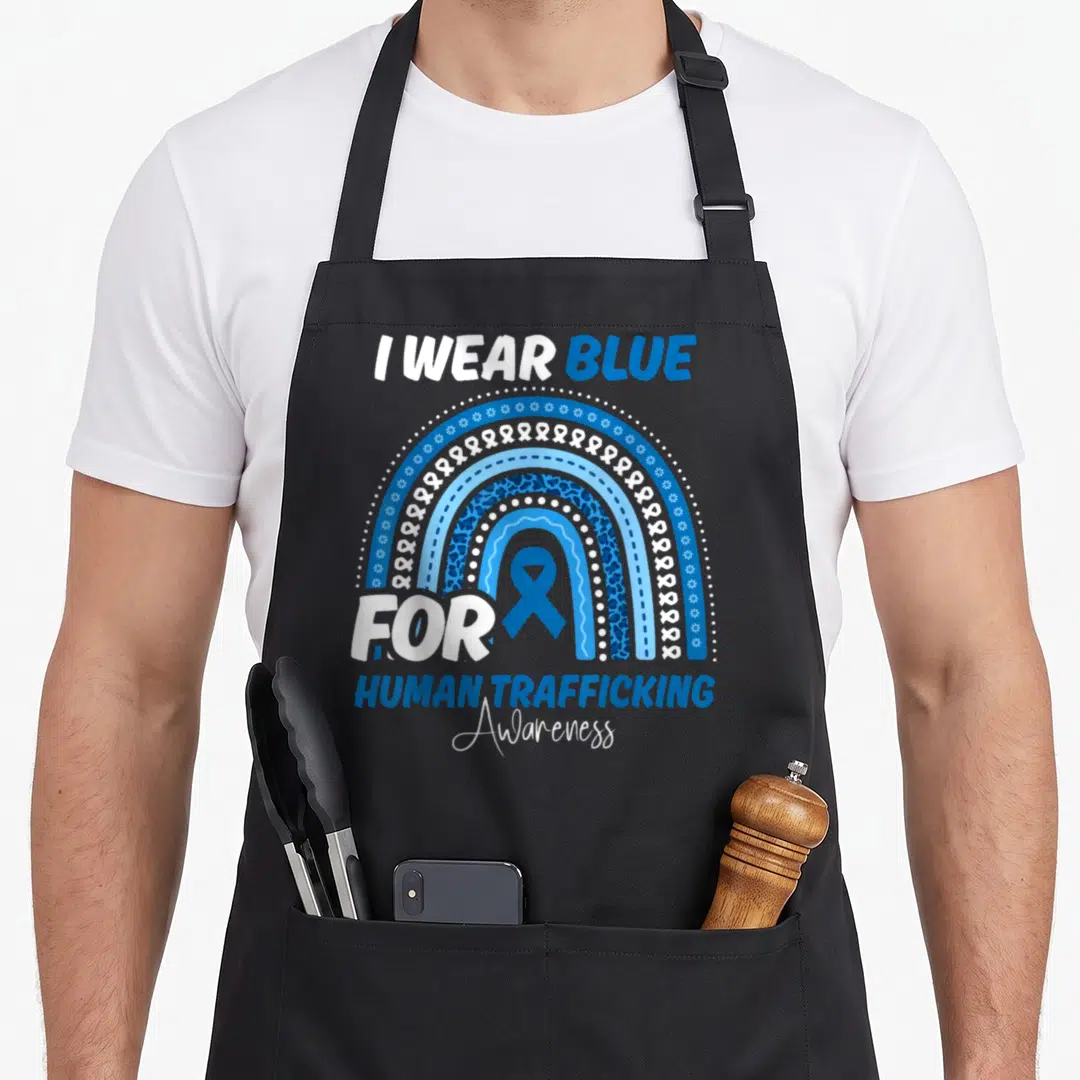 Trafficking rainbow apron - I WEAR BLUE FOR HUMAN TRAFFICKING Awareness text with blue ribbon inside rainbow arch — shown on a black cotton canvas apron against a white background