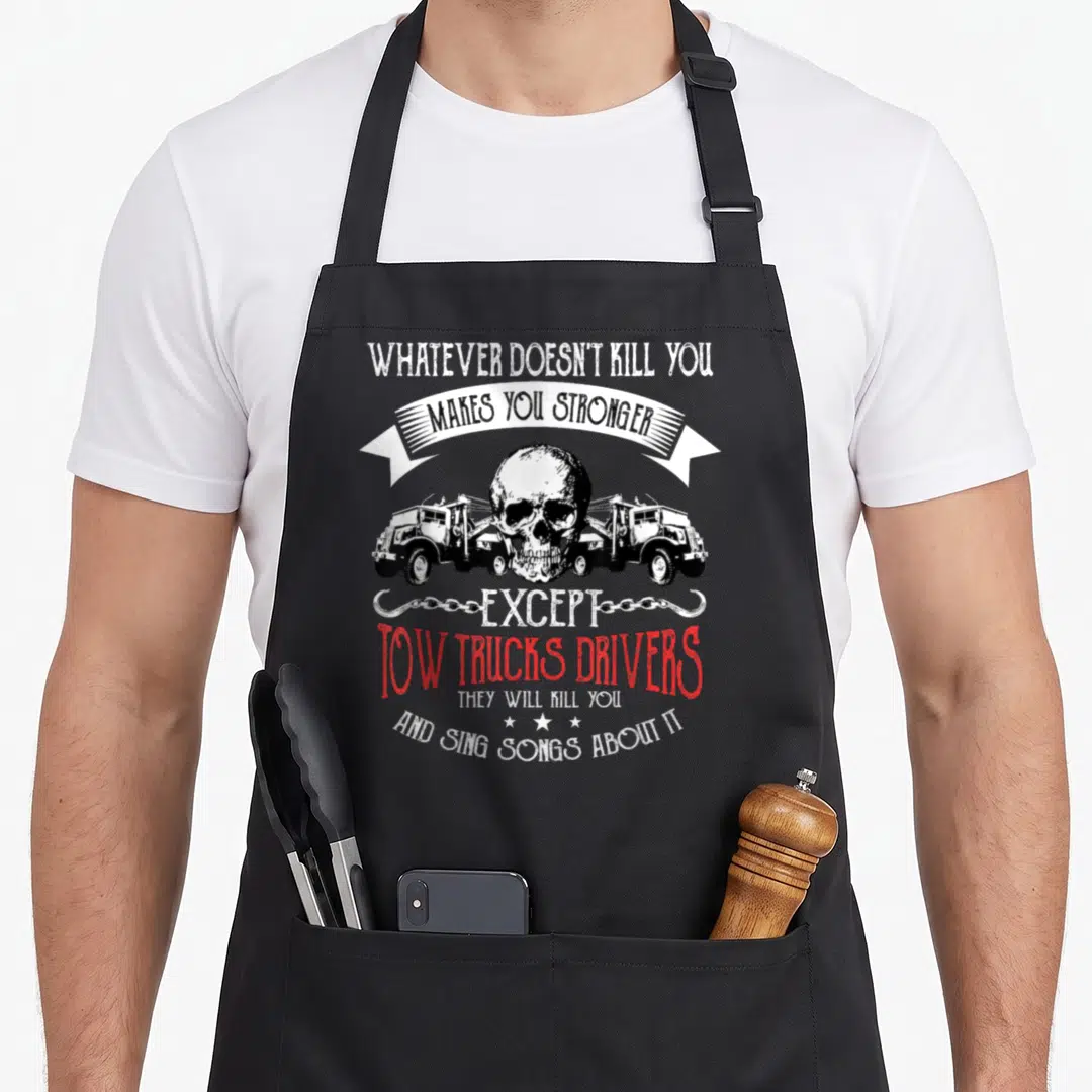 Stronger truck apron - Skull and two tow trucks with sarcastic white and red text on black fabric — shown on a black cotton canvas apron against a white background