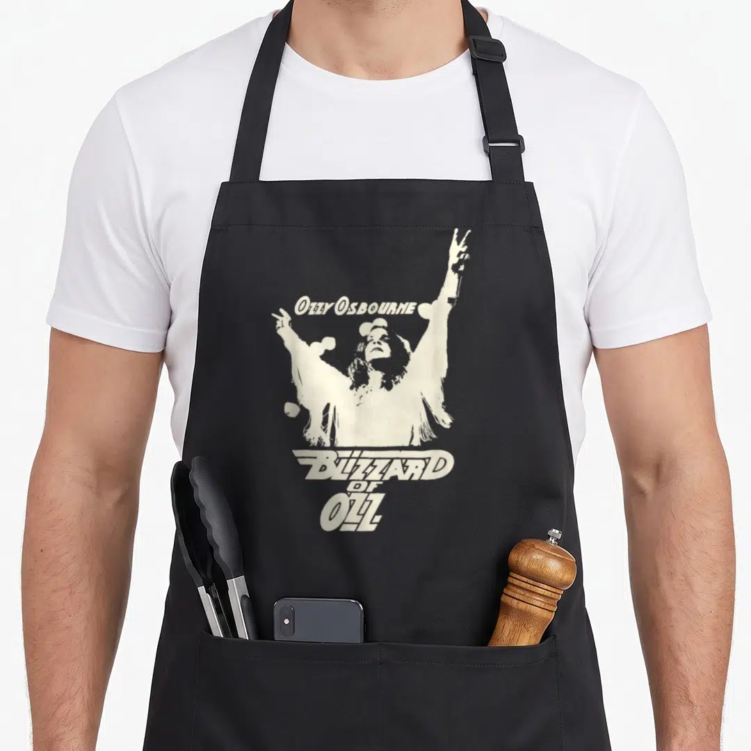 Blizzard ozzy osbourne apron - Off-white Ozzy Osbourne figure with raised arms and stacked Blizzard of Ozz text on black — shown on a black cotton canvas apron against a white background