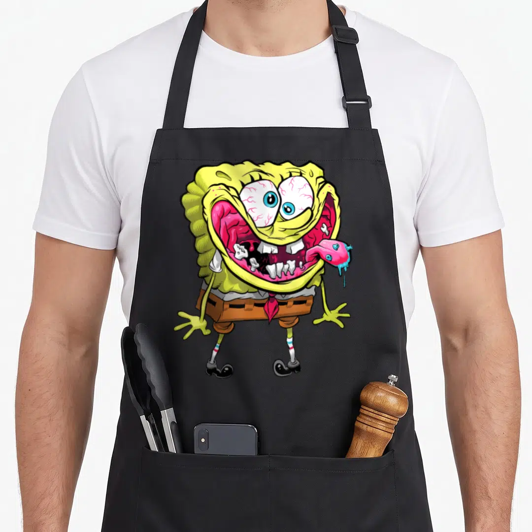 Wired general apron - Zombie sponge character with bloodshot eyes, jagged teeth, and detached tongue in cartoon style — shown on a black cotton canvas apron against a white background
