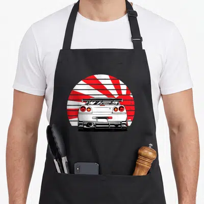 Tuner design imports vintage apron - White car rear view illustration against red and white rising sun rays in line art — shown on a black cotton canvas apron against a white background