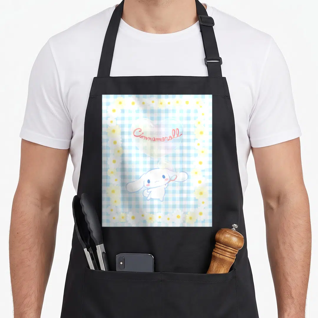 Bubble cinnamoroll apron - Cinnamoroll character with wand under text bubble on blue gingham with daisy border — shown on a black cotton canvas apron against a white background