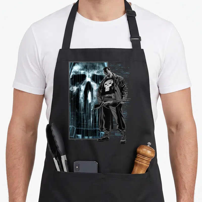 Bullet skull apron - Realistic man holding shotgun before large skull and brick wall in black white blue — shown on a black cotton canvas apron against a white background