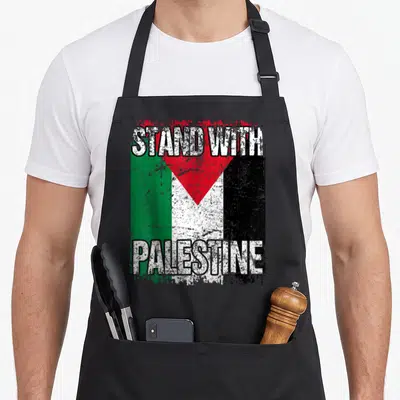 Stand palestine palestinian apron - STAND WITH PALESTINE text over distressed red green white black flag design — shown on a black cotton canvas apron against a white background