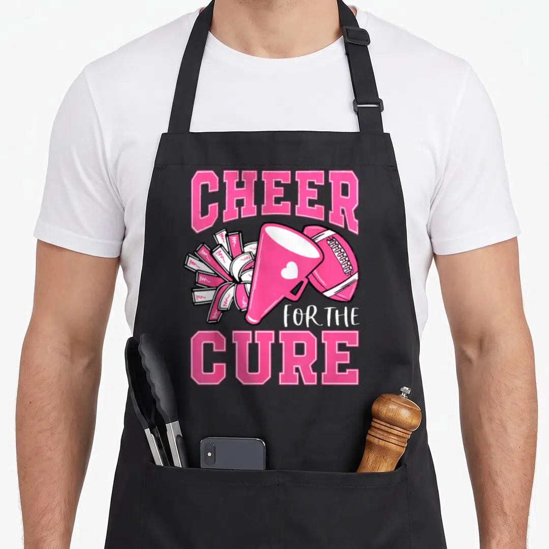 Cheer breast cancer awareness aprons - Pink megaphone football and pom-poms with CHEER FOR THE CURE text — shown on a black cotton canvas apron against a white background